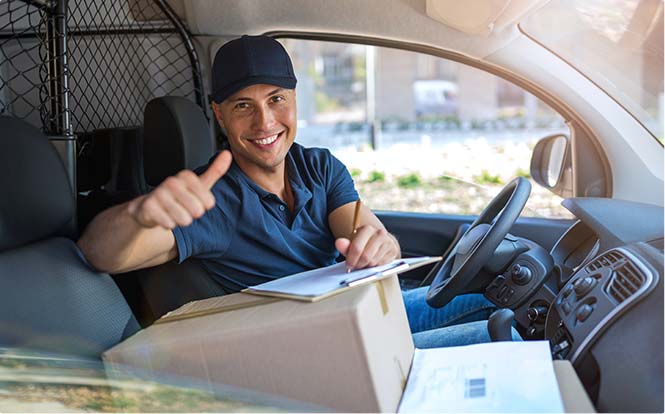 Smiling delivery man sitting with boxes in his van stock image